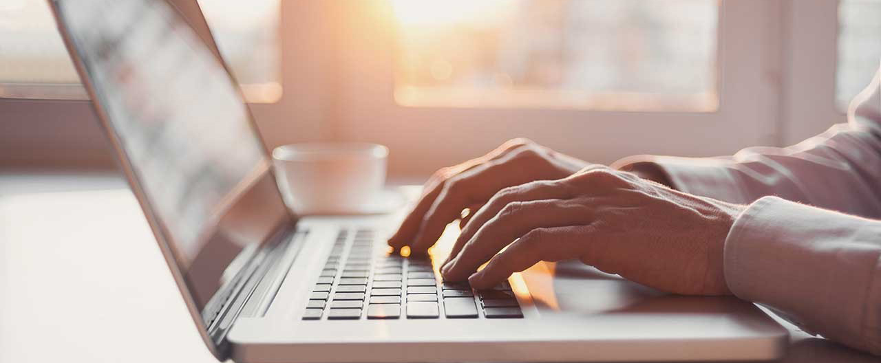 person typing on a laptop at sunset