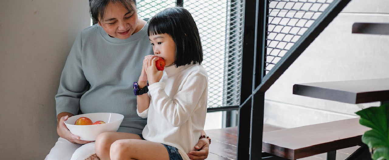 mother and child sitting on stairs eating apple